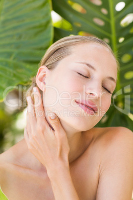 Beautiful blonde smiling at camera behind leaf