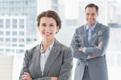 Smiling businesswoman looking at camera with colleague in backgr