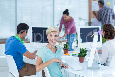 Smiling young woman working with her colleague at desk