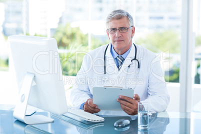 Smiling doctor working on computer at his desk