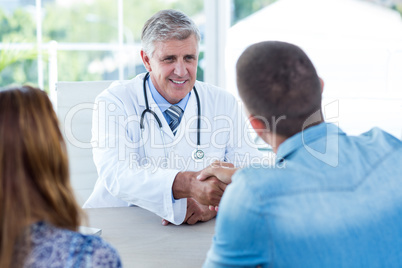 Smiling doctor greeting happy couple