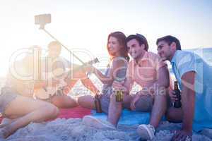 Happy hipsters taking pictures with selfie stick