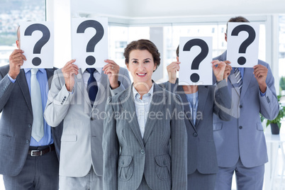 Business colleagues hiding their face with question mark sign