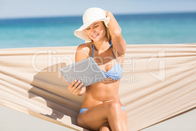 Pretty woman holding tablet pc in the hammock