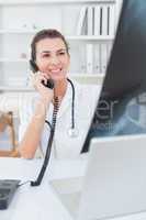 Doctor doing phone call while she using computer