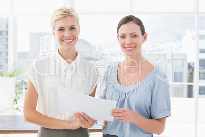 Smiling businesswomen looking at camera and working together