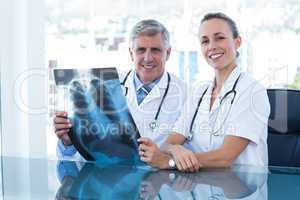 Smiling doctors looking at camera and holding xray