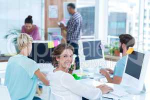 Smiling young woman working with her colleague at desk