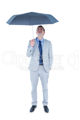 Businessman sheltering under umbrella