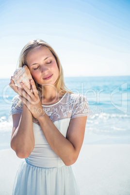 Lovely woman listening to a shell