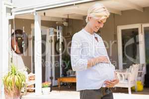 Smiling blonde pregnant hand on his belly