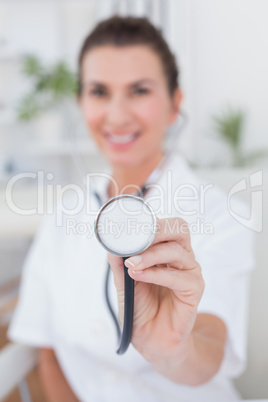 Happy doctor showing stethoscope to camera