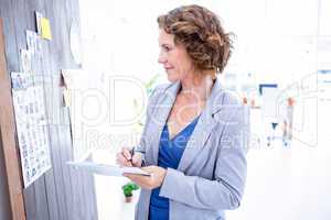 Creative businesswoman looking at pictures and taking notes