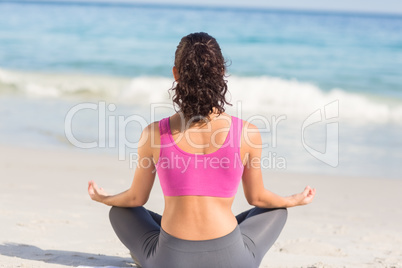 Wear view of fit woman doing yoga beside the sea