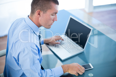 Businessman using his laptop and his smartphone