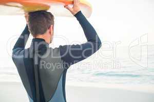 Man in wetsuit with a surfboard on a sunny day