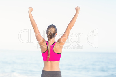 Wear view of fit woman looking at the sea with arms rise