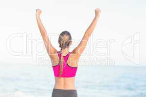 Wear view of fit woman looking at the sea with arms rise