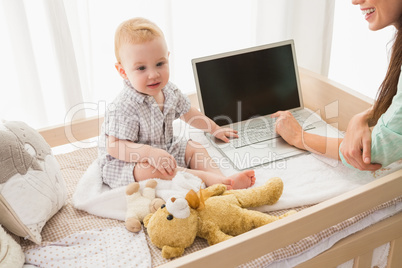 Happy mother using laptop with her baby boy