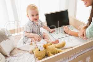 Happy mother using laptop with her baby boy