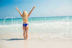 Pretty blonde woman with arms outstretched at the beach