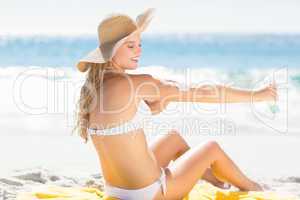 Pretty blonde woman spreading sun tan lotion on her arms