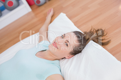 Woman looking at camera and relaxing on exercise mat