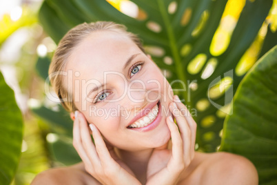 Beautiful blonde smiling at camera behind leaf