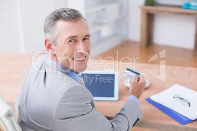 Smiling businessman holding tablet and credit card