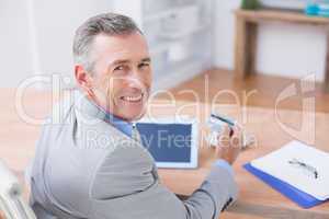 Smiling businessman holding tablet and credit card