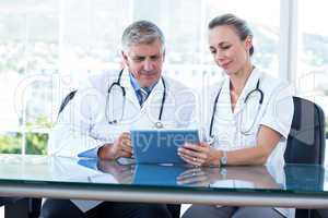 Smiling doctors working together on tablet