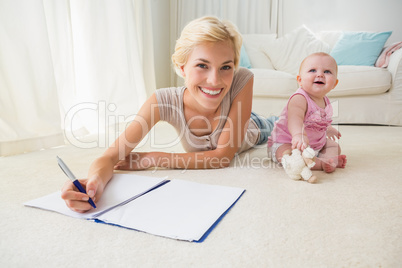 Happy blonde mother with her baby girl writting on a copybook