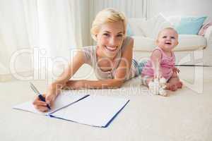 Happy blonde mother with her baby girl writting on a copybook