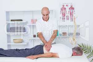 Physiotherapist doing back massage to his patient