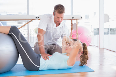 Trainer working with woman on exercise mat