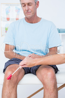 Doctor checking reflexes of the knee of her patient
