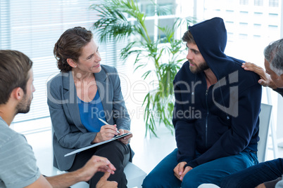 Concerned man comforting another in rehab group