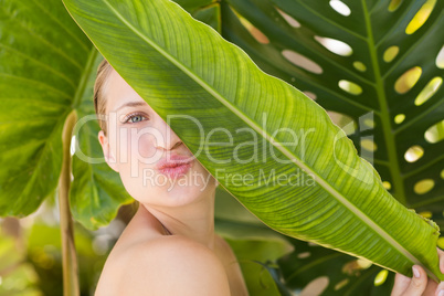 Beautiful blonde smiling at camera behind leaf