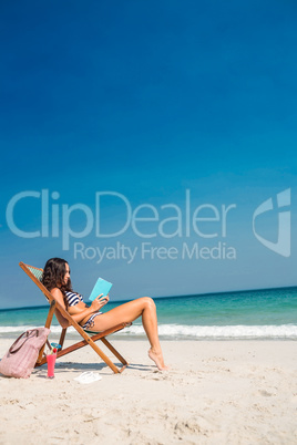 Pretty brunette reading a book on deck chair