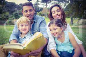 Happy familly reading a book in the park