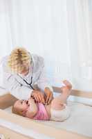 Beautiful cute baby girl with blonde doctor using stethoscope