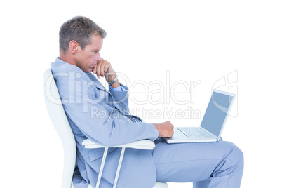 Handsome businessman sitting on a swivel chair and using his lap