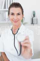 Happy doctor showing stethoscope to camera