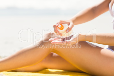 Close up view of Pretty blonde woman putting sun tan lotion on h