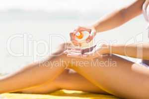 Close up view of Pretty blonde woman putting sun tan lotion on h