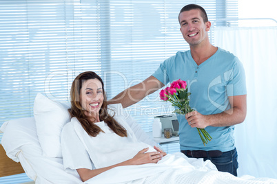 Handsome man offering bouquet of flowers to his pregnant wife