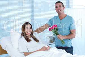 Handsome man offering bouquet of flowers to his pregnant wife