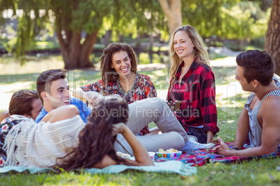 Happy friends in the park having picnic and playing guitar