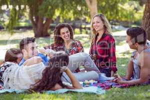 Happy friends in the park having picnic and playing guitar