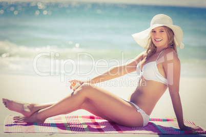 Pretty blonde sitting on a towel smiling at camera